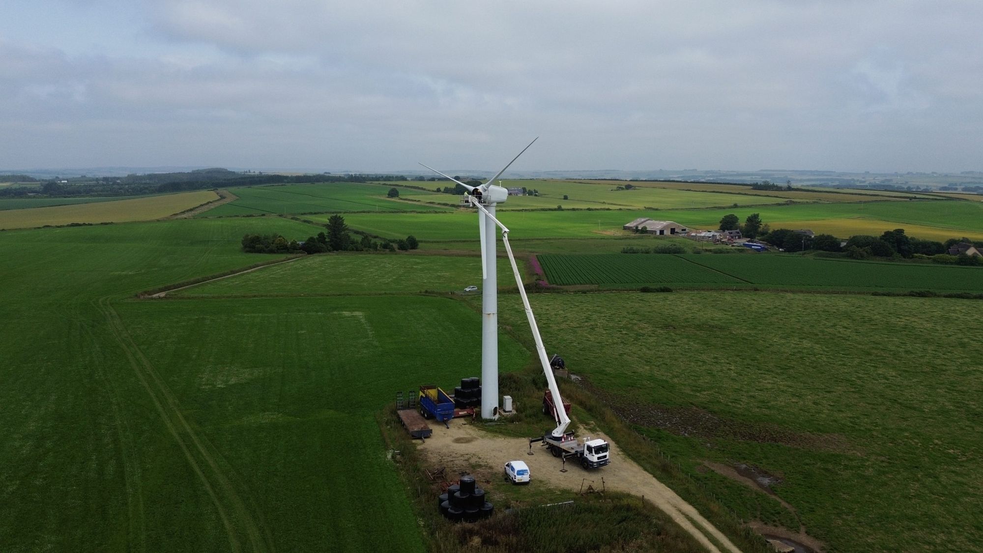 Engineers servicing a farm wind turbine from a cherry picker